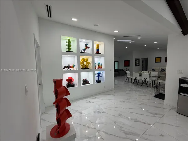 a large white kitchen with wooden floors a refrigerator and white cabinets