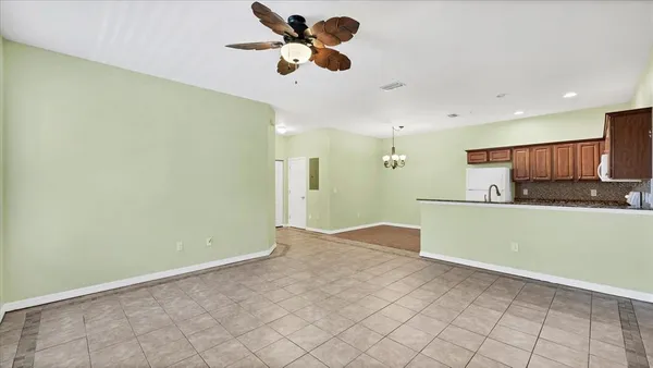 a view of kitchen and empty room with wooden floor