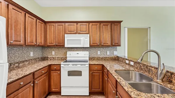 a kitchen with kitchen island granite countertop a sink a stove and cabinets
