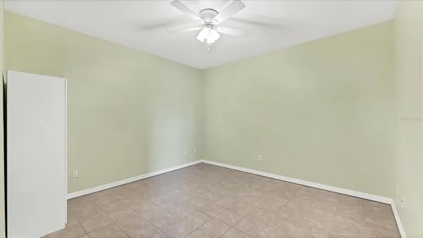 an empty room with a fan & a window