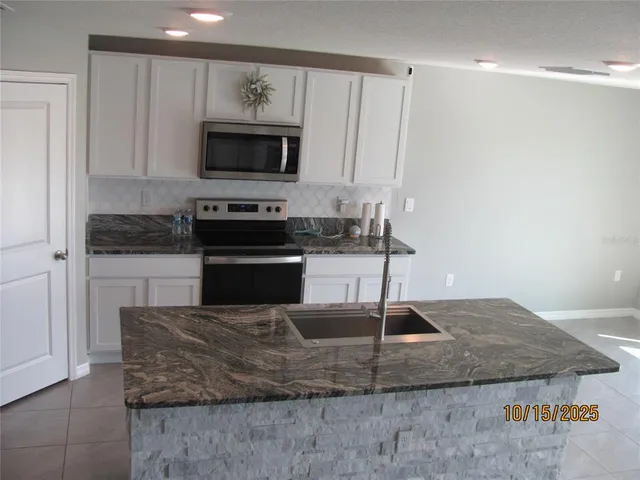 a kitchen with kitchen island granite countertop a sink and a stove