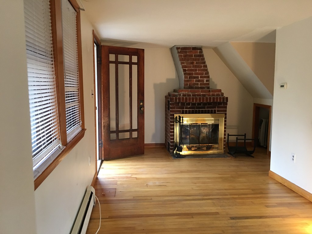 185 Shirley Road Lancaster, MA 01523 - Photo 3 of 15 a view of an empty room with wooden floor fireplace and a window