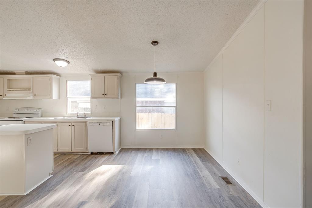 317 6th Street Joshua, TX 76058 - Photo 9 of 36 a kitchen with wooden floors white cabinets and window