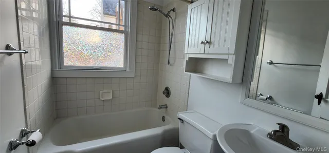 a bathroom with a tub sink and mirror