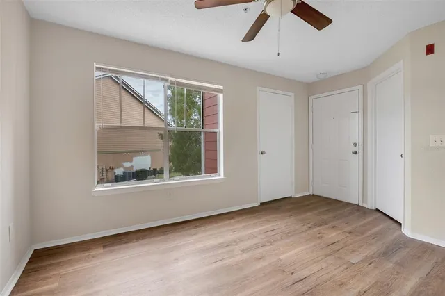 a view of an empty room with a window and wooden floor