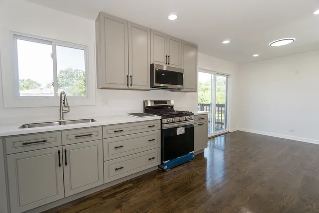 a kitchen with stainless steel appliances granite countertop a stove a sink and a microwave