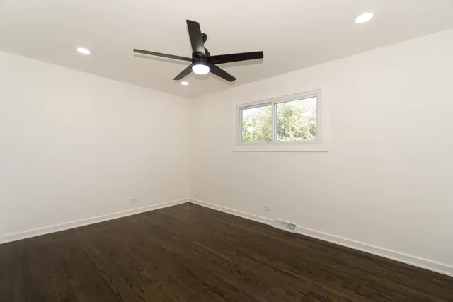 an empty room with wooden floor ceiling fan and window