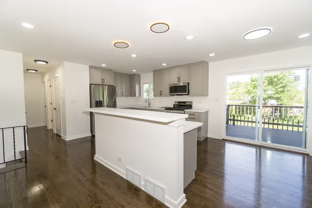 a kitchen with stainless steel appliances granite countertop a refrigerator a stove top oven a sink and a large window