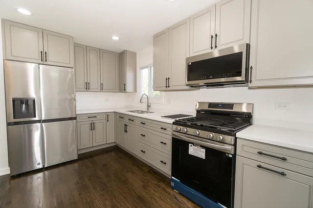 a kitchen with cabinets stainless steel appliances and wooden floor