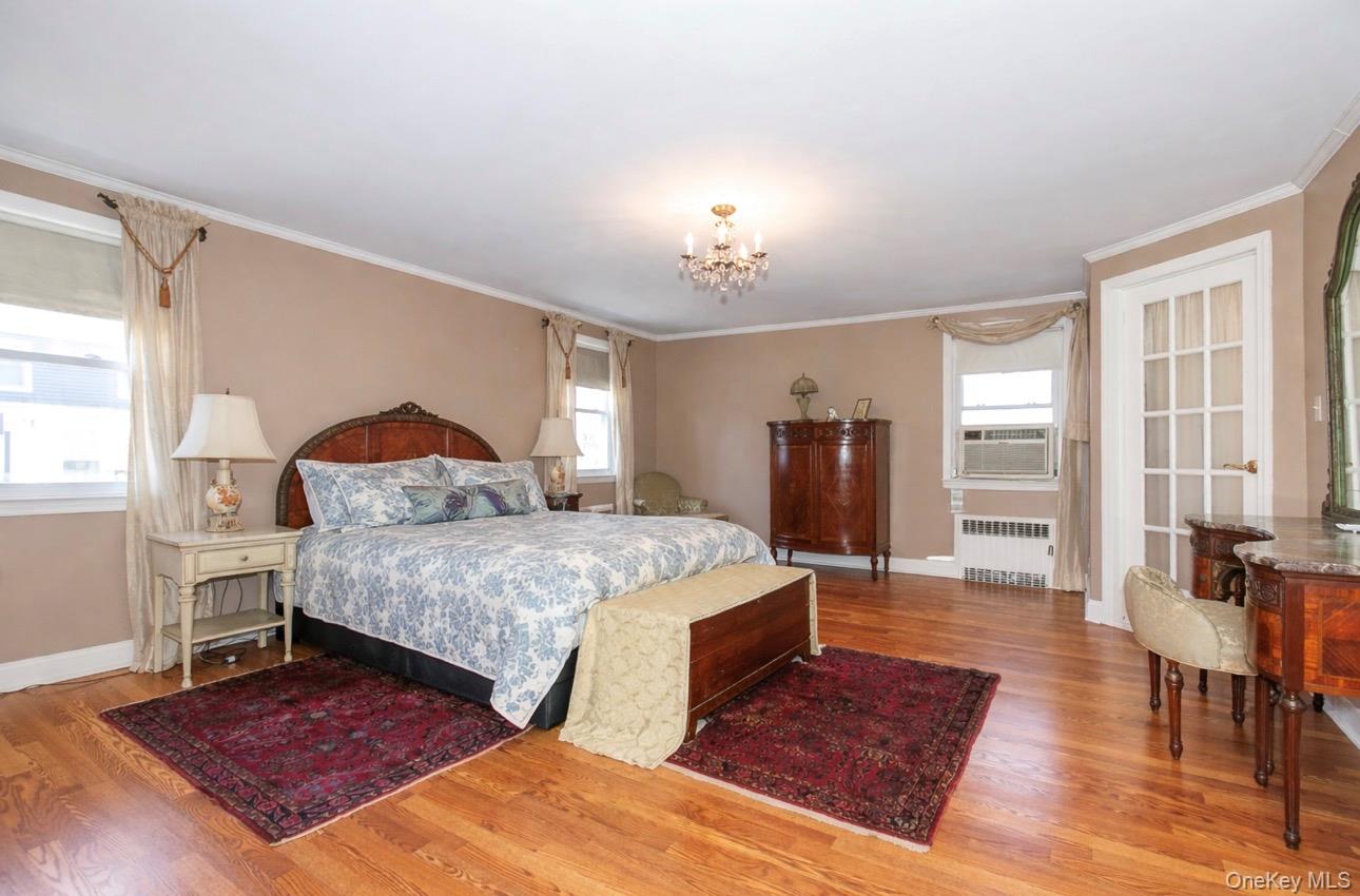 8 Plymouth Road Great Neck, NY 11023 - Photo 14 of 25 a spacious bedroom with a bed and wooden floor