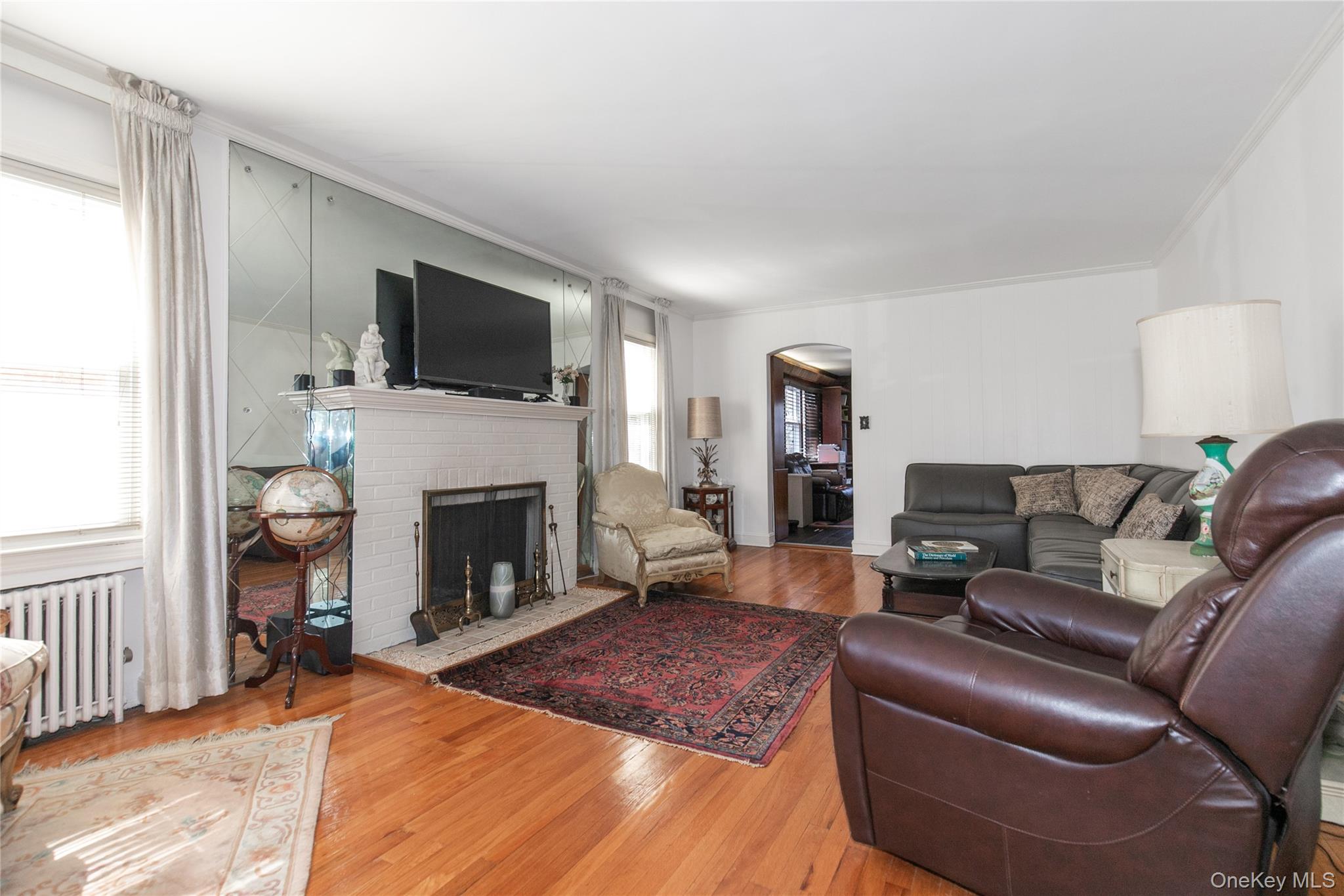 8 Plymouth Road Great Neck, NY 11023 - Photo 3 of 25 a living room with furniture a fireplace and a flat screen tv