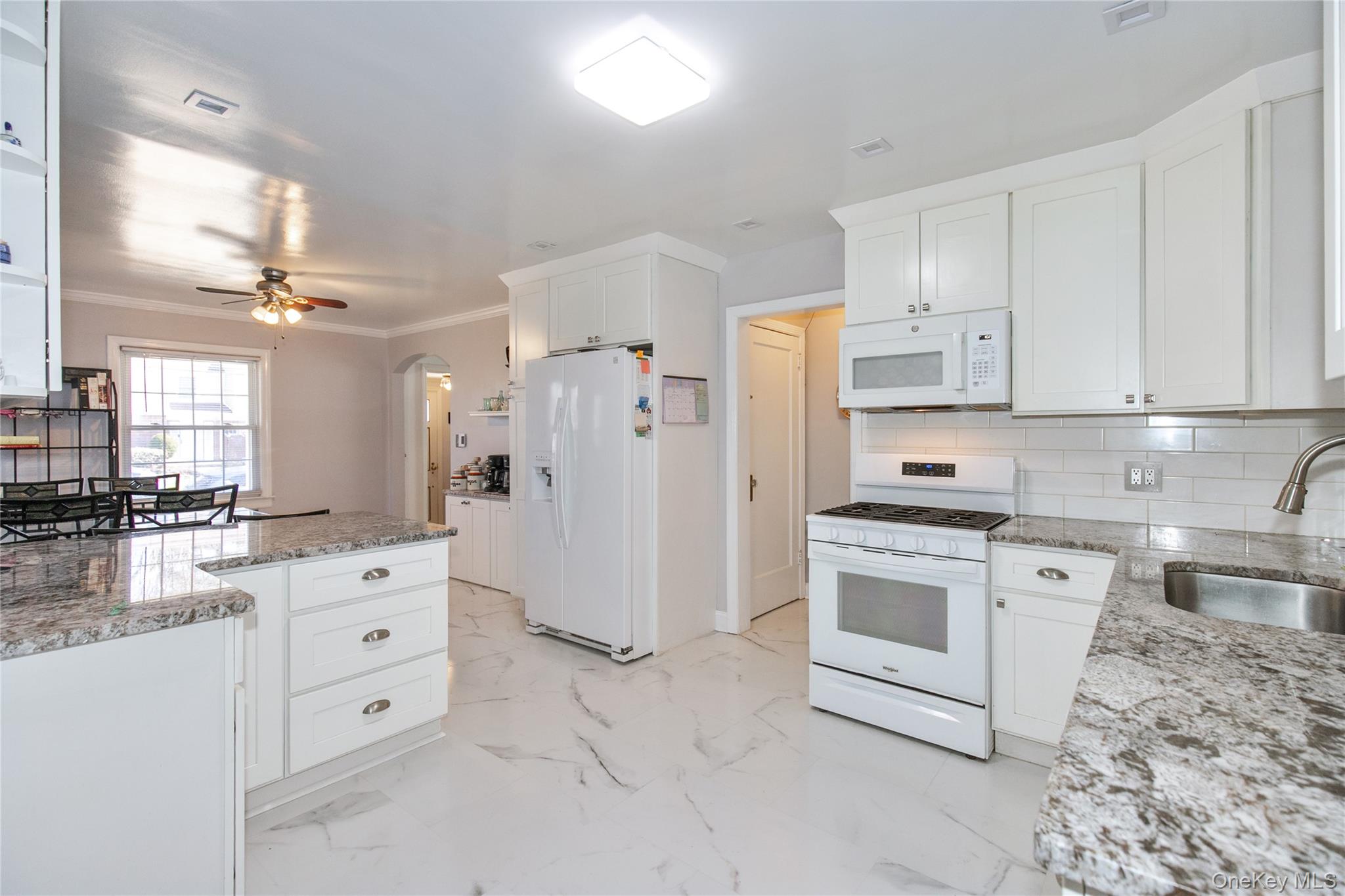 8 Plymouth Road Great Neck, NY 11023 - Photo 7 of 25 a kitchen with white cabinets and white appliances