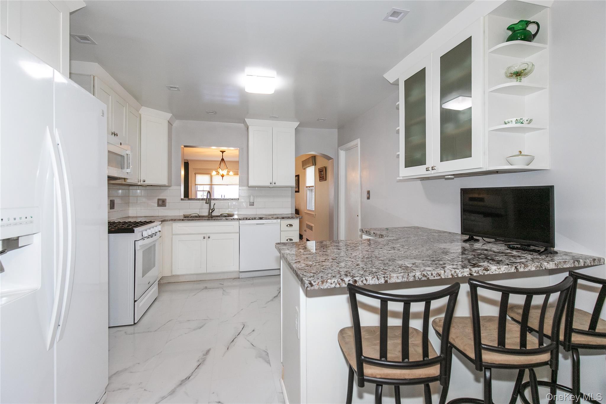 8 Plymouth Road Great Neck, NY 11023 - Photo 10 of 25 a kitchen with a dining table chairs and refrigerator