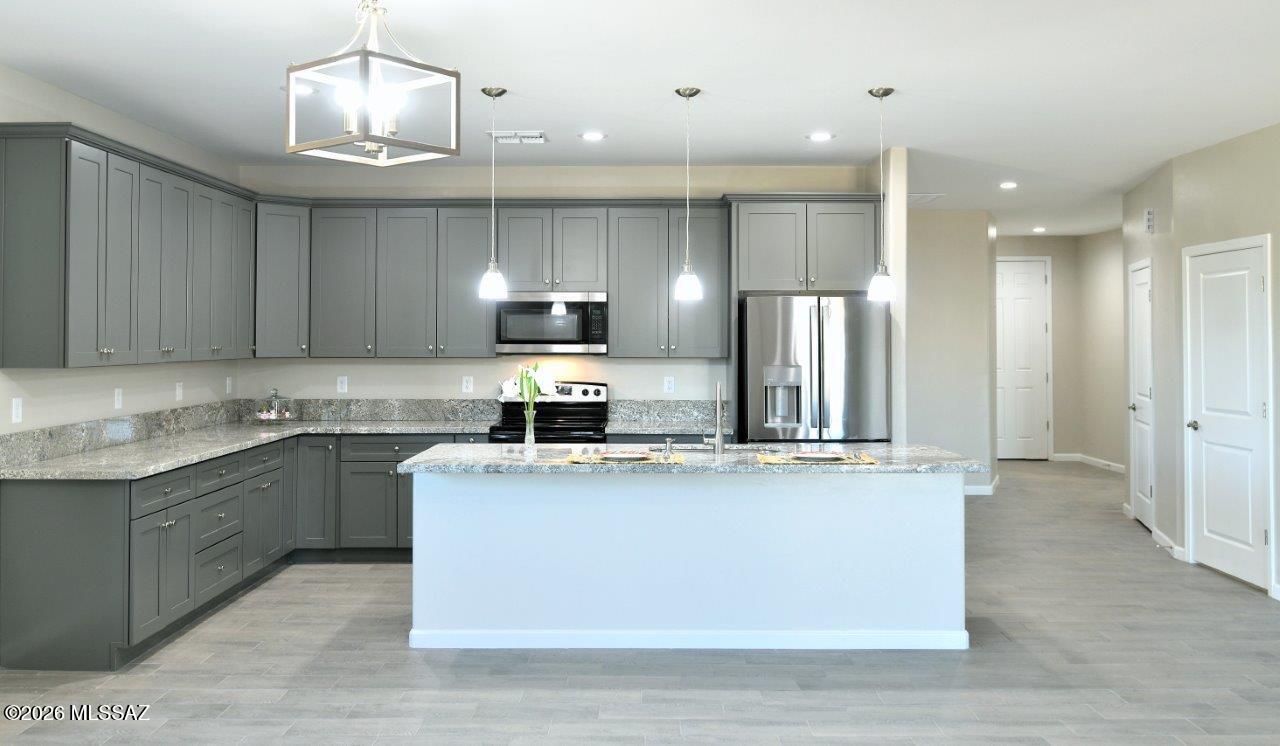 1091 North Vail View Road Vail, AZ 85641 - Photo 11 of 43 a kitchen with stainless steel appliances granite countertop a sink a stove a refrigerator and island with wooden floor