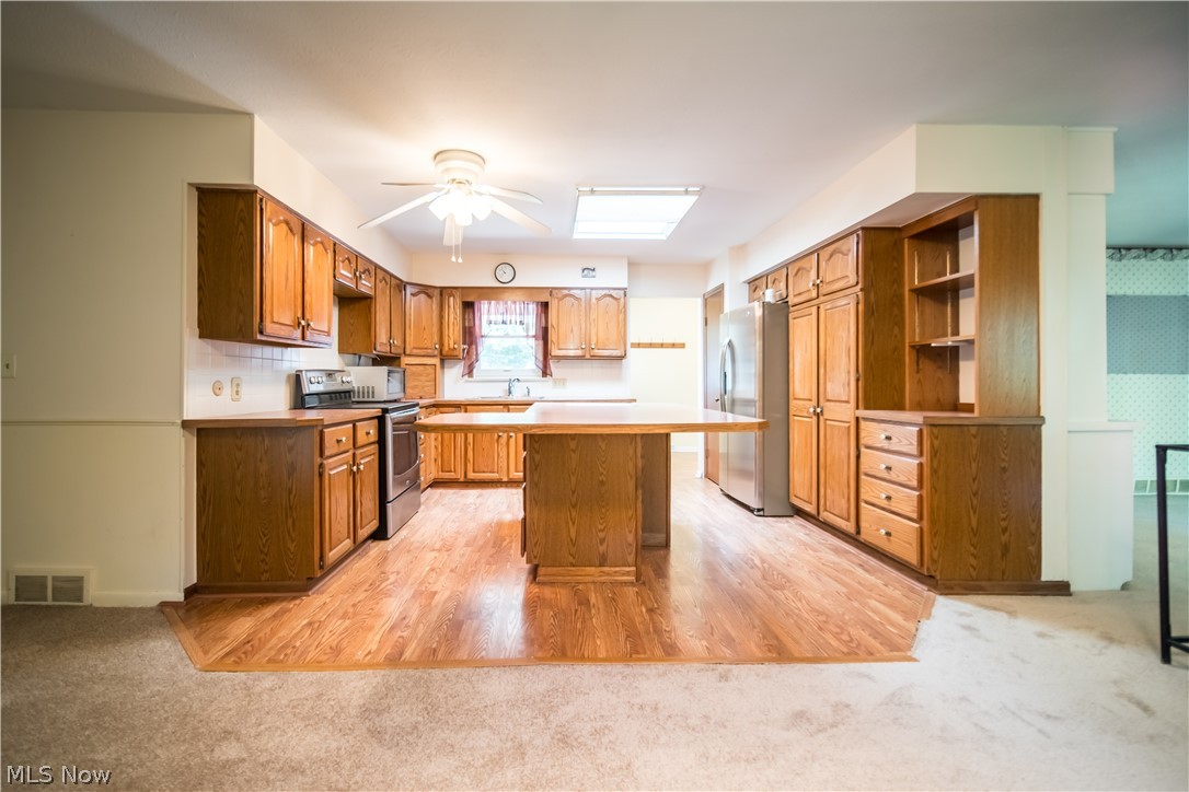 11063 Diagonal Road Mantua, OH 44255 - Photo 5 of 40 Kitchen featuring light wood-type flooring, ceiling fan, stainless steel appliances, and a skylight