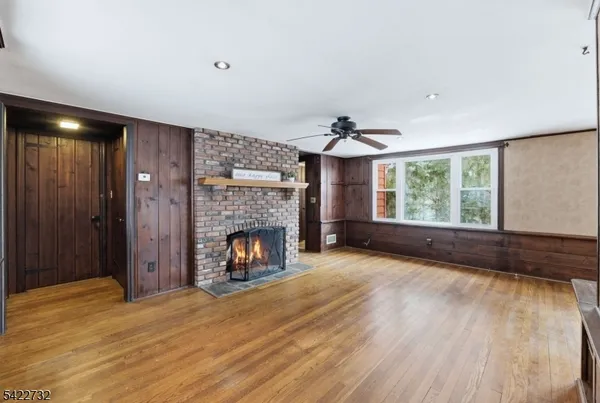 a view of an empty room with wooden floor fireplace and a window