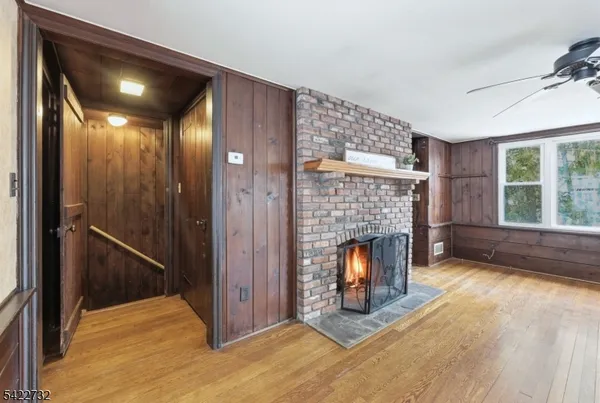 a view of an empty room with wooden floor fireplace and a window