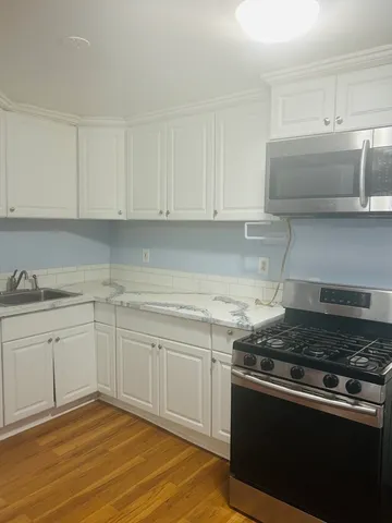 a kitchen with granite countertop white cabinets and stainless steel appliances