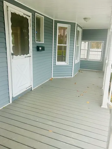 a view of an empty room with wooden floor and door