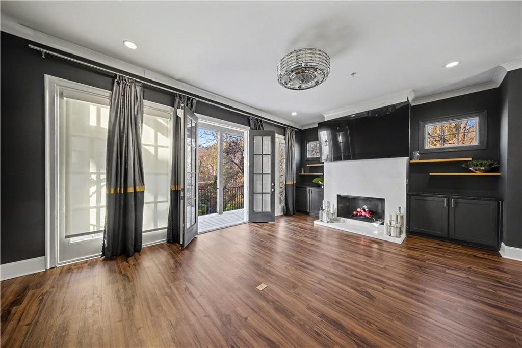 2067 Wheaton Way Atlanta, GA 30328 - Photo 16 of 64 an empty room with wooden floor a fireplace and windows