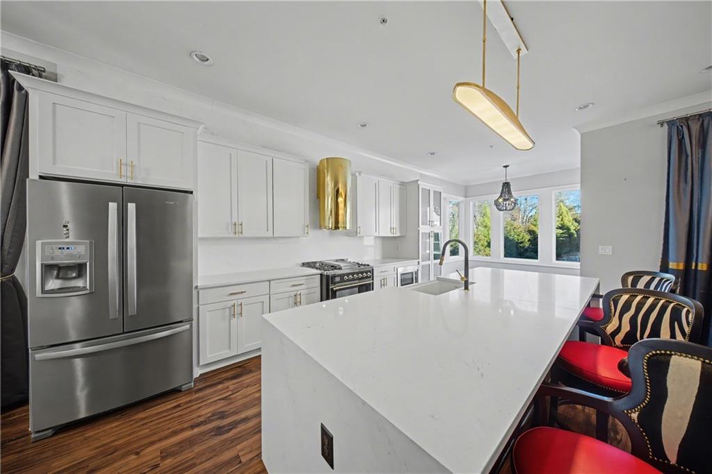 2067 Wheaton Way Atlanta, GA 30328 - Photo 27 of 64 a kitchen with stainless steel appliances a refrigerator a sink a stove a dining table and chairs with wooden floor