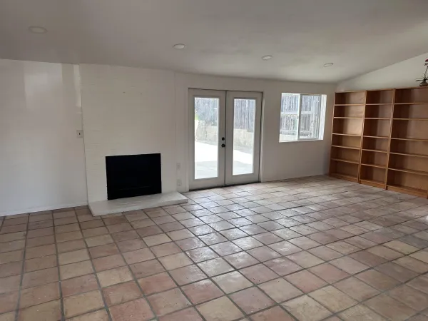 a view of an empty room with a window and a fireplace