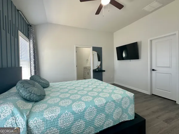 a bedroom with a bed and a flat tv screen on dresser