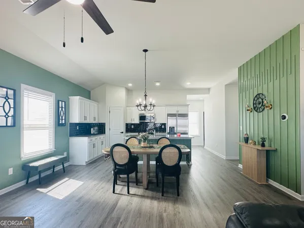 a view of a dining room and livingroom with furniture wooden floor a rug a painting and a chandelier