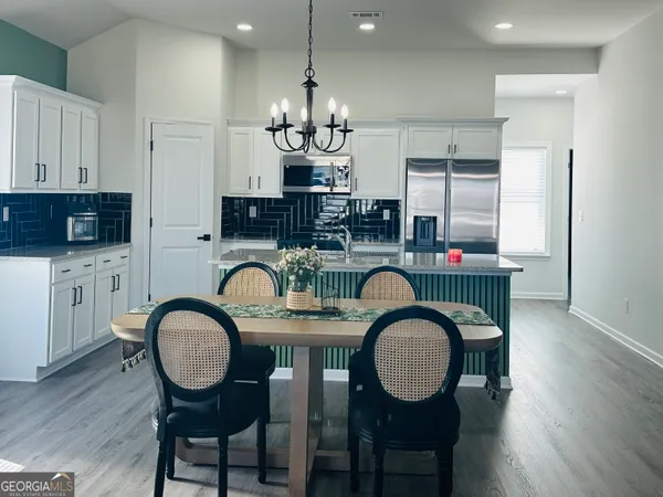 a dining room with wooden floor a chandelier a glass table and chairs