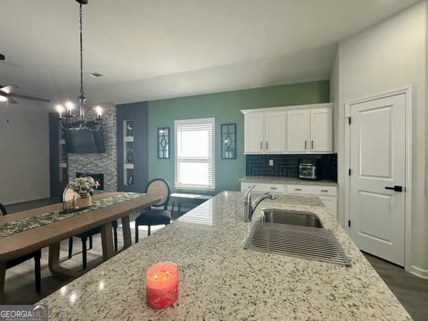a kitchen with granite countertop a stove a sink a dining table and chairs