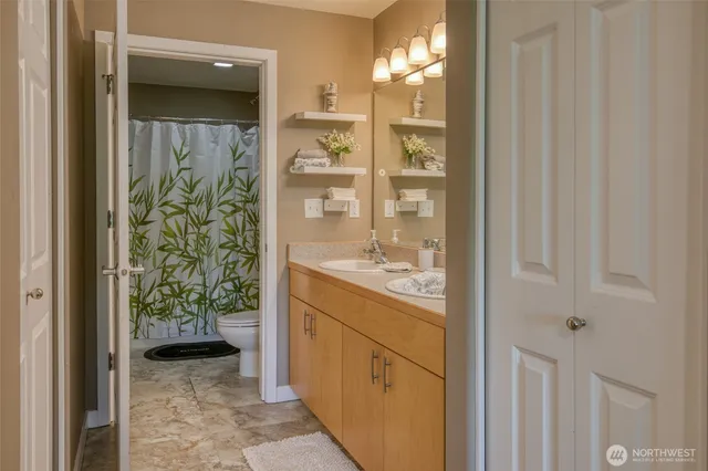 a bathroom with a granite countertop sink a toilet and shower