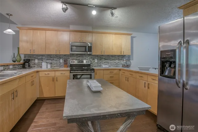 a kitchen with stainless steel appliances granite countertop a sink a stove and refrigerator