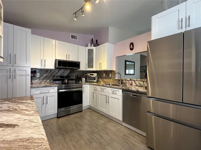 a kitchen with stainless steel appliances granite countertop a refrigerator stove and sink