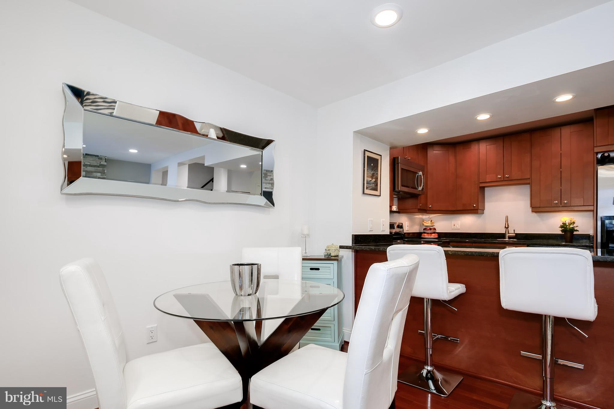1119 Harvard Street Northwest, Unit R Washington, DC 20009 - Photo 9 of 26 a kitchen with stainless steel appliances granite countertop a table chairs stove a sink dishwasher and cabinets with wooden floor