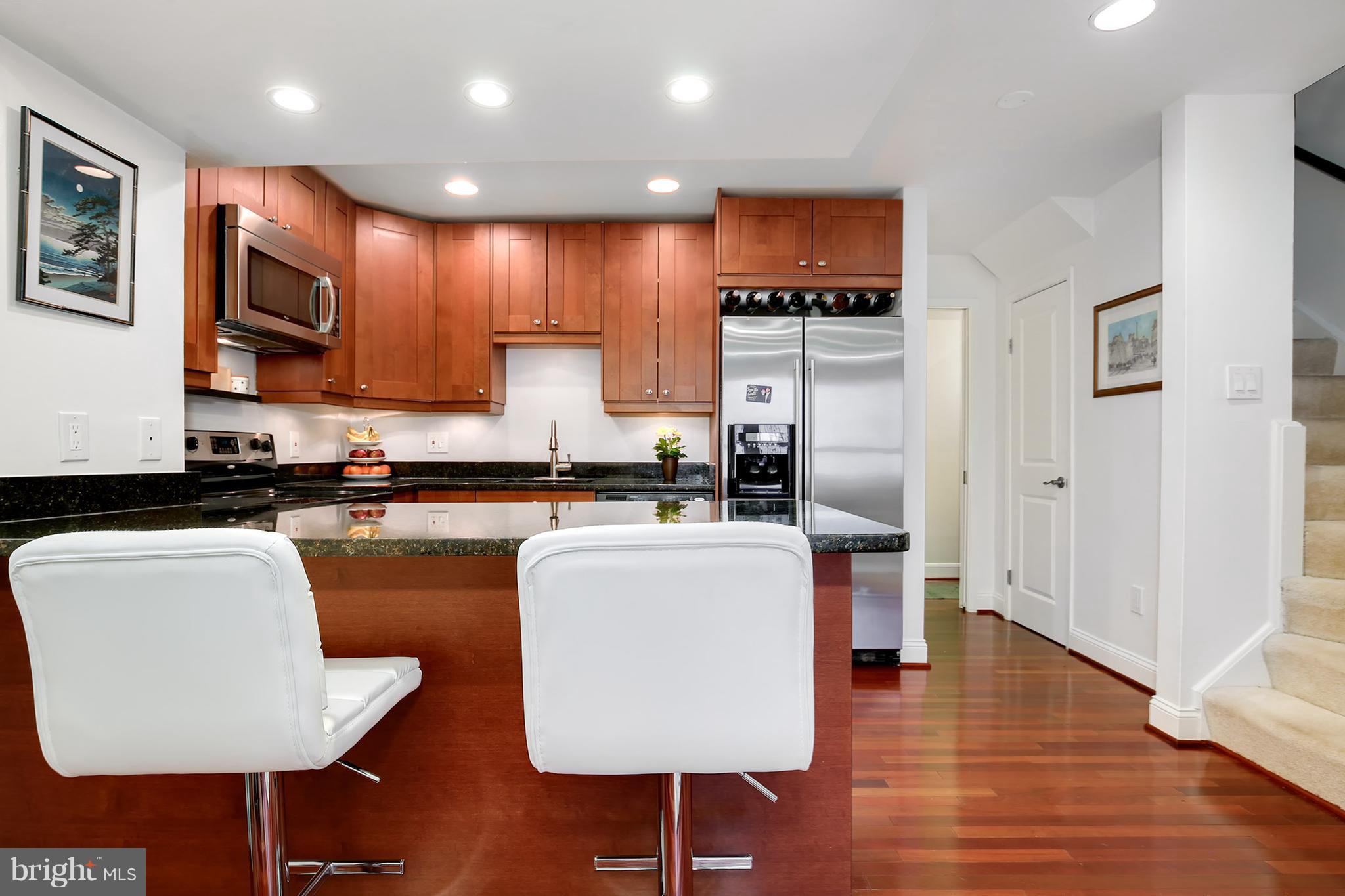 1119 Harvard Street Northwest, Unit R Washington, DC 20009 - Photo 10 of 26 a kitchen with kitchen island granite countertop wooden cabinets and a refrigerator