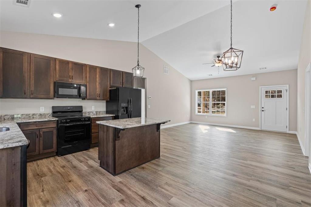 146 Old Brock Road Rockmart, GA 30153 - Photo 16 of 45 a kitchen with granite countertop a stove top oven a sink dishwasher a refrigerator and a dining table with wooden floor