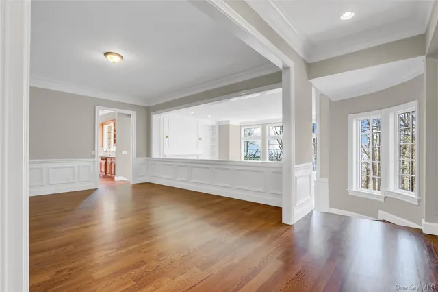 a view of an empty room with wooden floor fireplace and a window