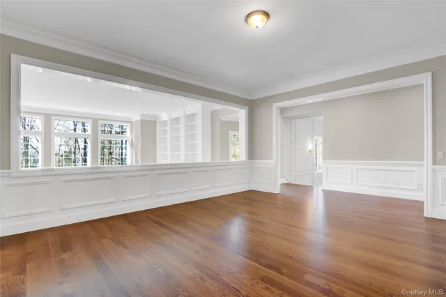 an empty room with wooden floor fireplace and windows