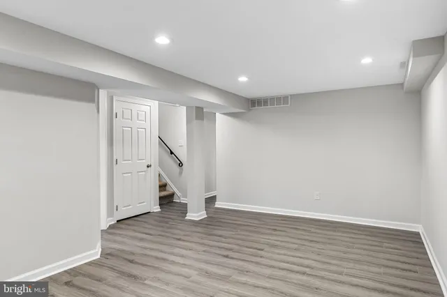 a view of an empty room with wooden floor and stairs