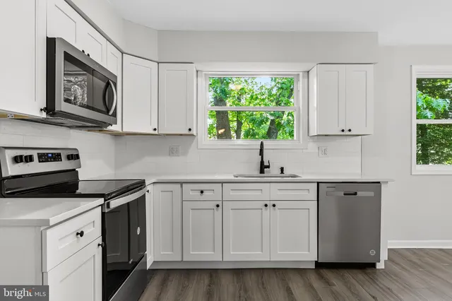 a kitchen with stainless steel appliances granite countertop white cabinets granite counter tops and a window