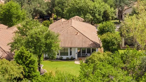 an aerial view of a house with green yard and outdoor seating