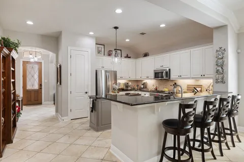 a kitchen with stainless steel appliances granite countertop a refrigerator and a stove top oven