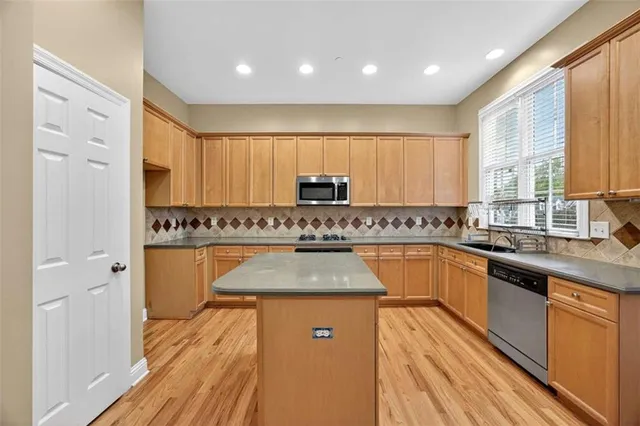 a kitchen with stainless steel appliances granite countertop wooden cabinets a stove top oven a sink and dishwasher with wooden floor