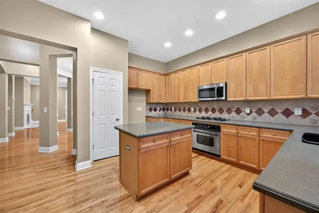 a kitchen with stainless steel appliances granite countertop wooden cabinets a stove a sink and dishwasher with wooden floor