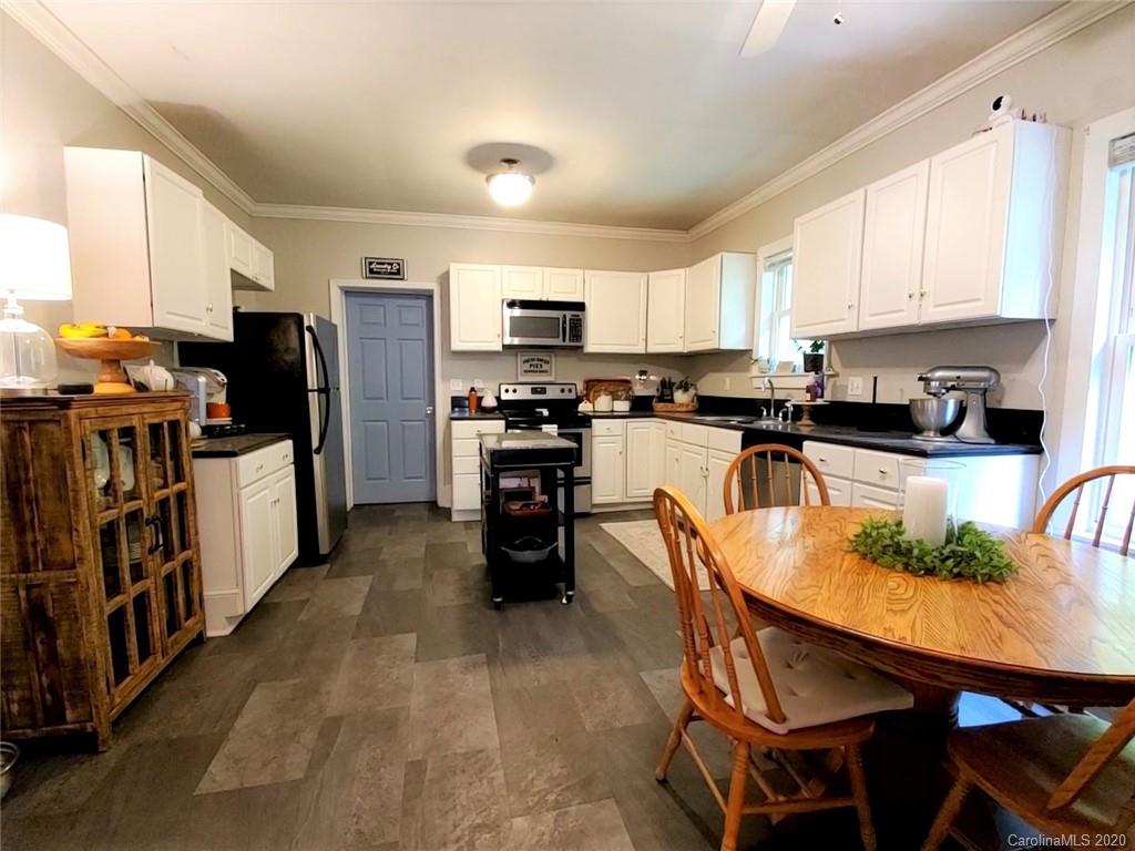 1602 Griffith Road Monroe, NC 28112 - Photo 11 of 45 a kitchen with stainless steel appliances granite countertop a stove top oven a sink dishwasher a dining table and chairs with wooden floor