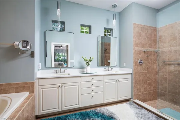 a bathroom with a double vanity sink a mirror a bathtub and shower