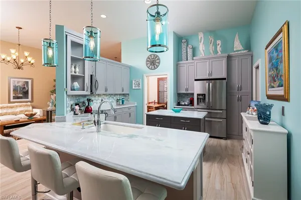 a kitchen with stainless steel appliances granite countertop a dining table chairs and a refrigerator