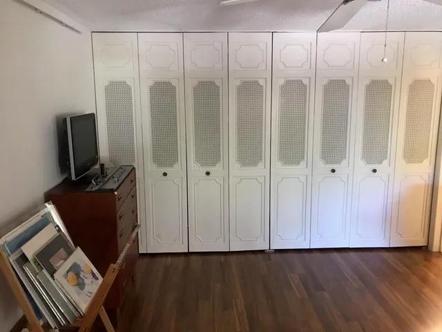 a view of an empty room with wooden floor and a cabinet