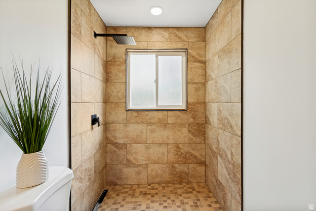 62 South Clark Lane Elk Ridge, UT 84651 - Photo 10 of 30 Jack and Jill Bathroom connected to primary bedroom. Walk-in shower featuring large format wall tiling, mosaic floor tiling, a frosted window, and matte black fixtures