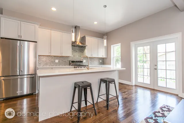 a kitchen with stainless steel appliances granite countertop a refrigerator a stove a sink dishwasher and white cabinets with wooden floor